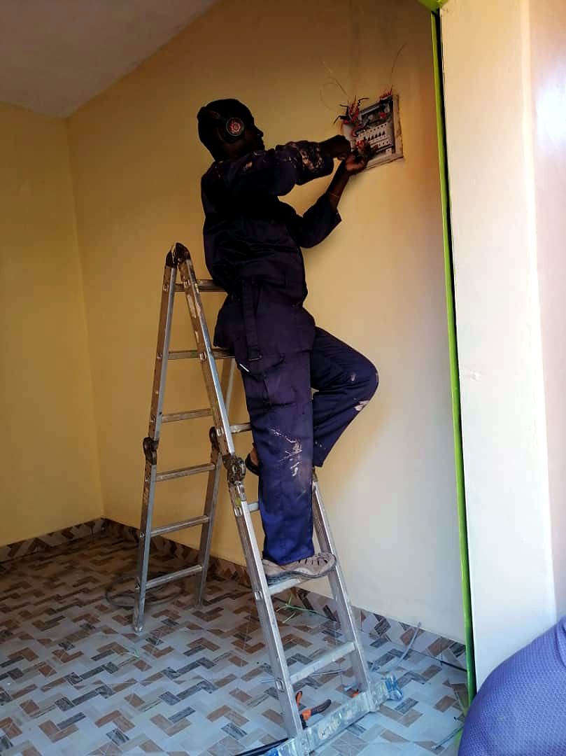 Technician on a step ladder connecting a distribution board in a new room