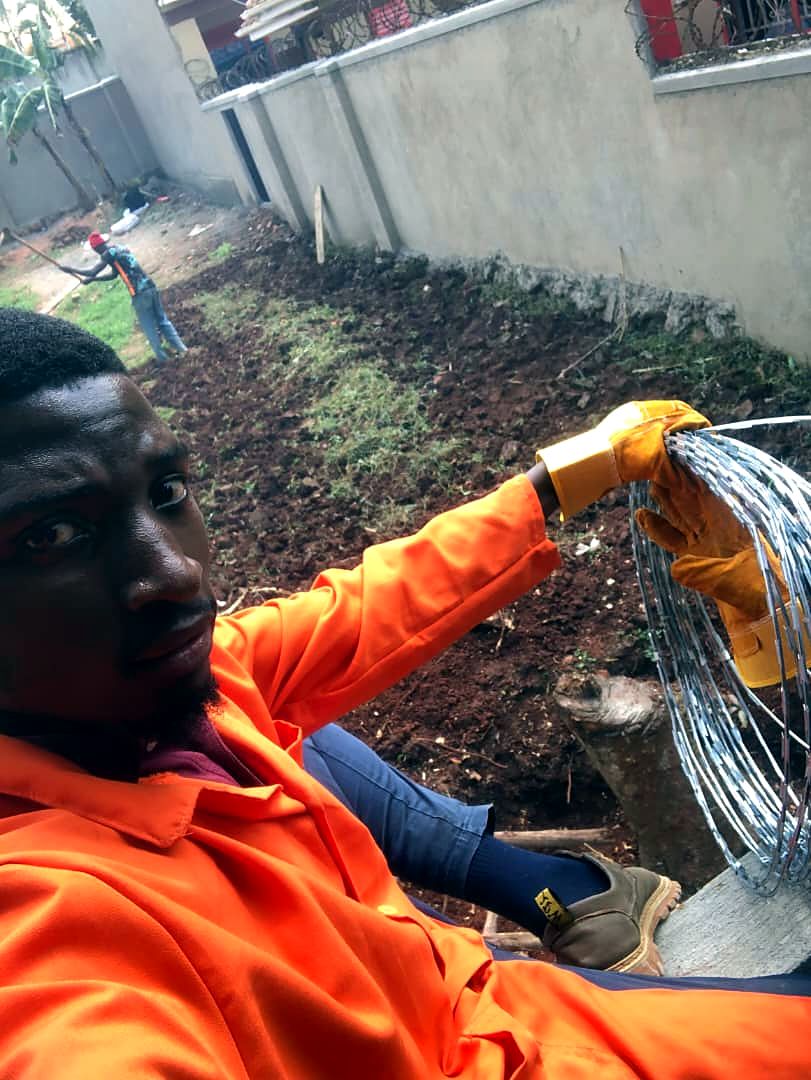 Technician in orange overalls holding razor wire during a perimeter installation