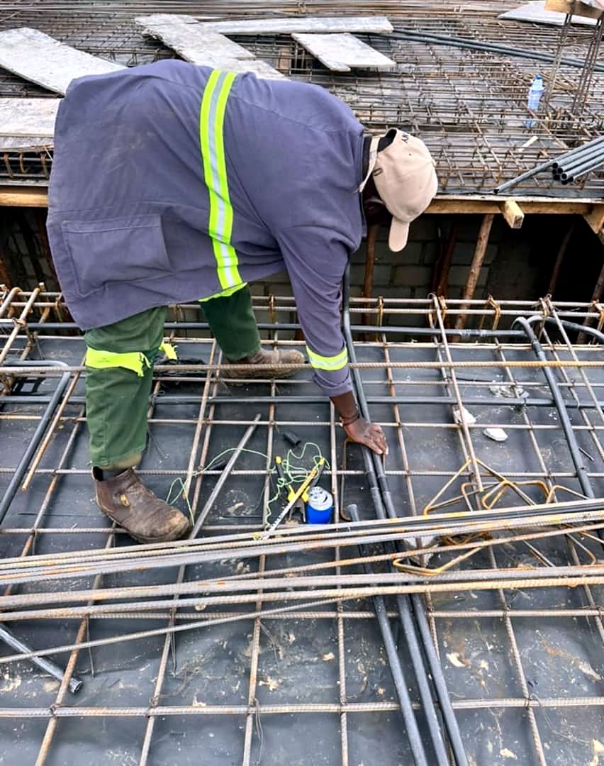 Technician fixing conduit boxes onto slab reinforcement