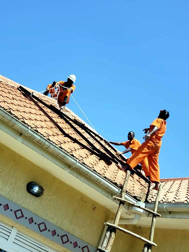 Three technicians on a steep tiled roof during a solar installation